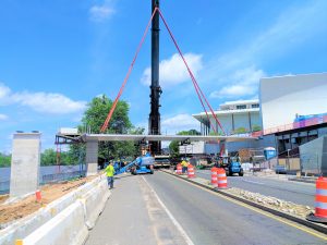 A pedestrian bridge being picked by a large crane